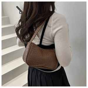 Détail de la texture tressée d'un sac à bandoulière croissant marron foncé pour femme