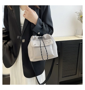 Detail der hellgrauen Nylon-Beuteltasche mit Kordelzugverschluss und vorderer Druckknopftasche