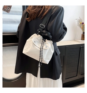Detailansicht der cremefarbenen Nylon-Beuteltasche mit Kordelzug und schwarzem Gurt