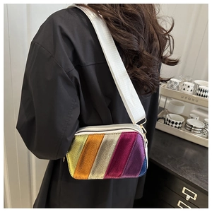 Detail of colorful metallic striped crossbody bag with white nylon strap and gold hardware