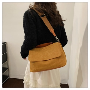 Detailed view of the brown faux suede handbag with wide fabric strap and golden buckle