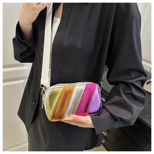 Detail of colorful metallic striped crossbody bag with wide white shoulder strap