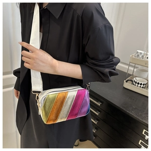 Close-up of vibrant iridescent striped crossbody bag with a white wide strap and gold hardware