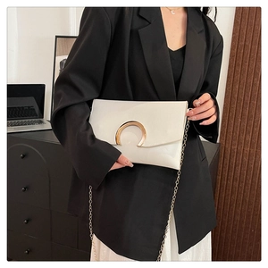 Detail of white leather envelope bag featuring gold C-buckle and elegant chain strap