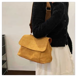 Detail of mustard yellow suede crossbody bag with wide canvas shoulder strap on a model