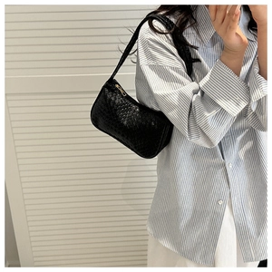 Detail of a black woven hobo shoulder bag with a secure golden zipper closure