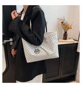 Detail of white tote bag with black M letter print and gold metallic charm