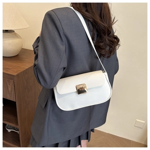 Vue détaillée d'un sac à bandoulière en cuir blanc avec boucle dorée sur un blazer gris