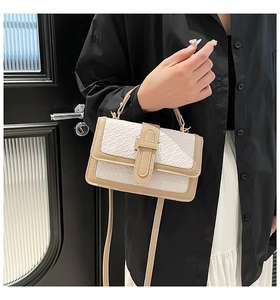 Detailed view of beige straw handbag with crocodile texture and golden lock clasp