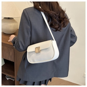 Detailed view of the white shoulder bag with a gold buckle worn with a gray suit