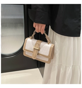 Detailed view of white crocodile pattern handbag with golden H buckle and tan trim detail