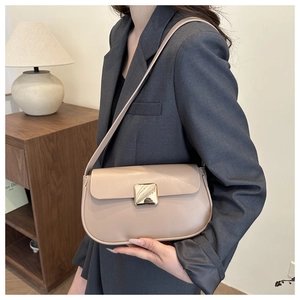 Close-up of beige minimalist underarm bag with a large golden square buckle on a model