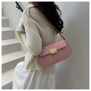 Sac à bandoulière en cuir rose avec boucle dorée, porté par un mannequin en extérieur