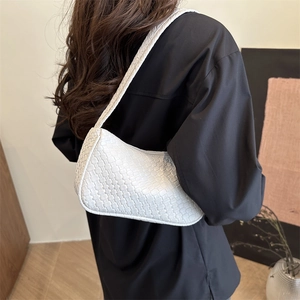 Minimalist white woven underarm bag styled by model for a chic modern fashion look