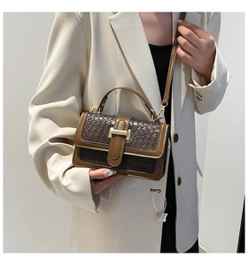Detail of the golden H-shaped clasp and crocodile embossed texture on a crossbody bag