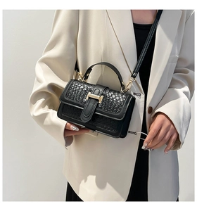 Detailed view of black woven texture leather bag with iconic golden H-shaped metal buckle