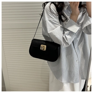 Detail of minimalist black leather shoulder bag with a polished gold square buckle