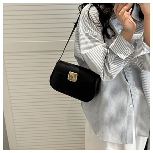 Detail of minimalist black leather square shoulder bag with gold metal buckle closure