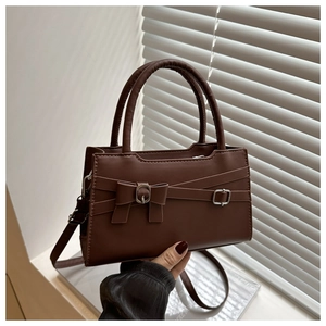 Detail of dark brown leather handbag with a bow accent and silver adjustable buckle