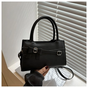 Detail of a black leather mini square bag with a bow belt and silver metal buckle