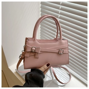 Detail of pink crossbody bag with leather cross straps, bow buckle and silver hardware