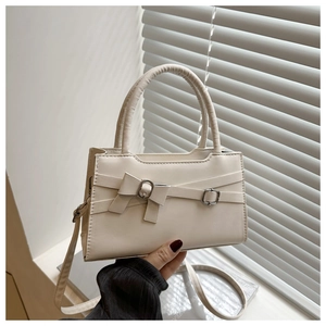 Detail of cream leather shoulder bag with decorative bow and silver metal buckles
