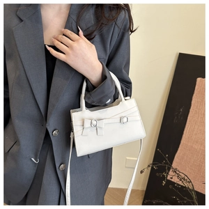 Detail of white PU leather crossbody bag featuring silver buckles and minimalist strap