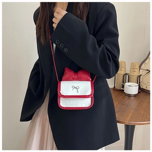 Detail of red and white bow shoulder bag with crocodile texture and silver charm