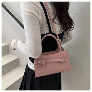 Détail du sac bandoulière rose avec nœud décoratif et boucle argentée sur la sangle