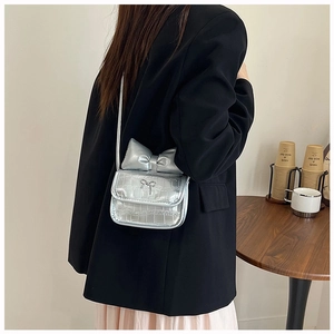 Detail of silver crocodile-embossed mini bag with large bow and chic metal clasp