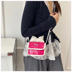 Detail of pink mini crossbody bag with large white bow and crocodile texture on a model