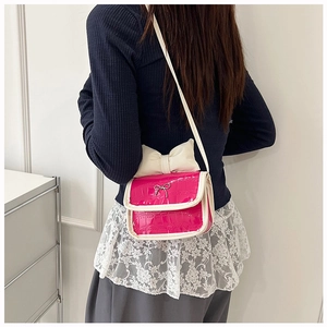 Detail of pink croc-embossed mini crossbody bag with a large white decorative bow