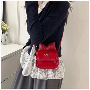 Detail of red crocodile pattern crossbody bag with large bow and metallic buckle