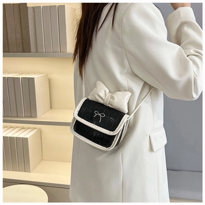 Close-up of contrast crossbody bag with bow detail and crocodile texture surface