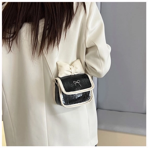 Detail of mini black faux-crocodile bag with large white bow and silver accents