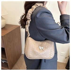 Detail of light brown woven underarm bag with butterfly clasp and ruched shoulder strap