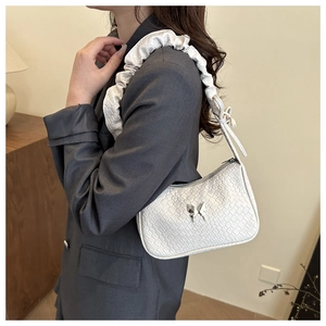 Close-up of white woven shoulder bag with silver butterfly buckle and cloud style strap