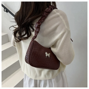 Gros plan sac tissé marron avec boucle papillon argentée et bandoulière à plis élégants