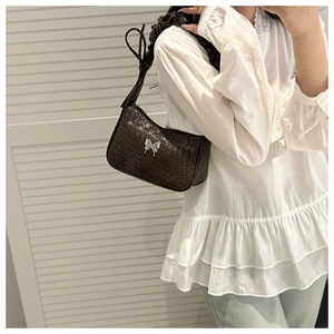Détail du sac à bandoulière tissé marron foncé avec boucle papillon et bandoulière froncée