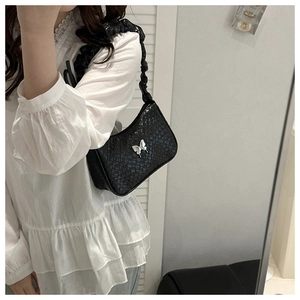 Détail du sac sous l'aisselle tissé noir avec papillon argenté et sangle ondulée