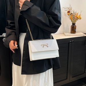 Petit sac blanc minimaliste avec chaîne, nœud doré et texture effet crocodile