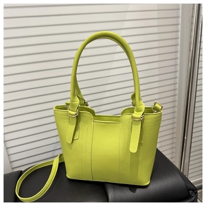 Detailed close-up of lime green faux leather handbag with golden metal rings and strap