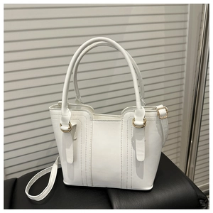 Top-down view of white leather bucket bag with gold ring hardware and stitching details