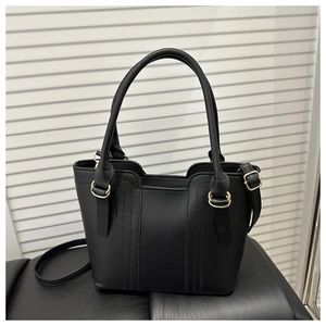 Detail view of black matte leather handbag with vertical stitching and gold hardware