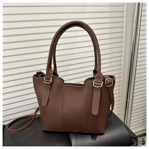 Detail of dark brown leather bucket bag with smooth texture and golden metal hardware