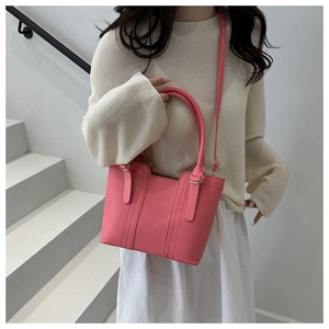 Lifestyle shot of elegant pink leather tote bag with vertical stitching and crossbody strap