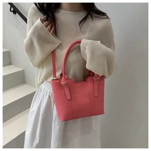 Modèle portant un sac seau rose en cuir avec poignée et détails dorés brillants