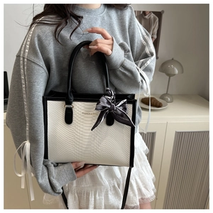 Close-up of white snake texture handbag with decorative scarf and shoulder strap detail