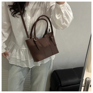 Detail of dark brown leather bucket bag with gold hardware and contrast stitching details