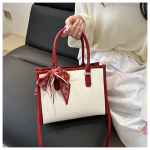 Detail of white crocodile textured tote with red trim and heart pattern silk scarf